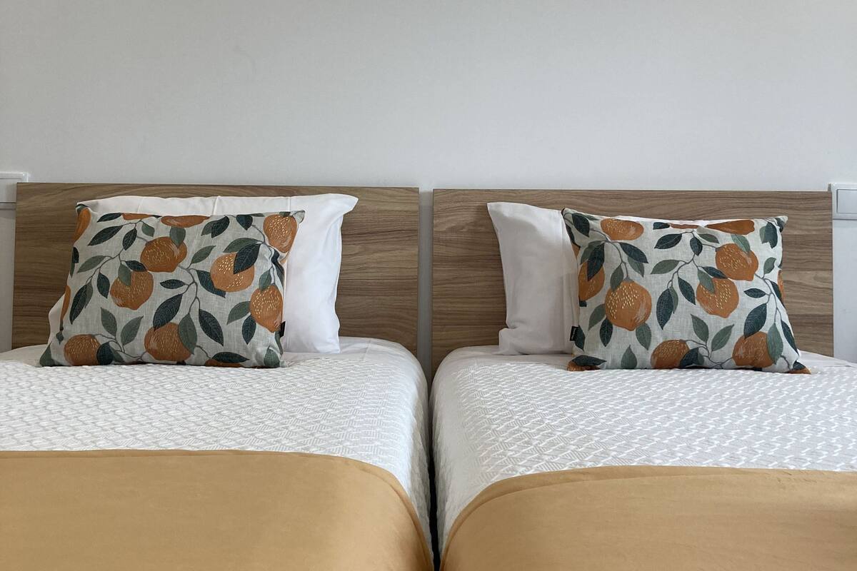 Two twin beds with matching headboards and white bedding.