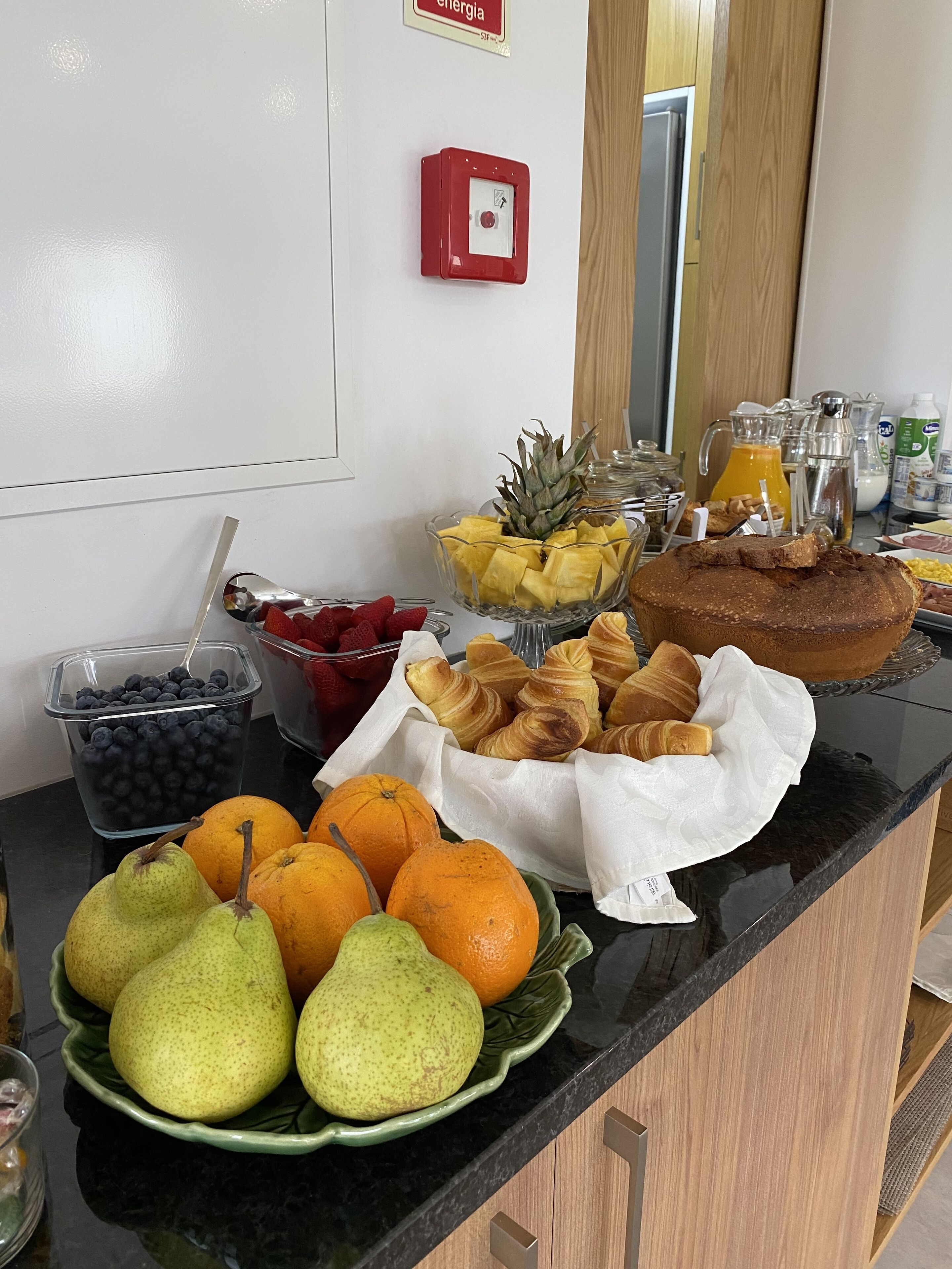 A breakfast buffet with fruits, pastries, and beverages.