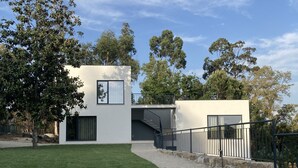 Un bâtiment moderne à deux étages, avec un chemin de pierre menant à une entrée fermée par un portail.