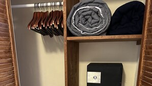 Un armario de madera con repisas, una barra para colgar ropa y una chaqueta doblada.