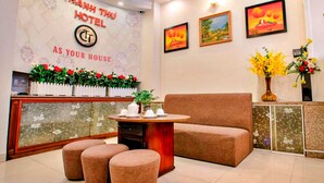 Zona de recepción de un hotel con diseño moderno, que incluye un mostrador de recepción, área de estar y obras de arte en las paredes.