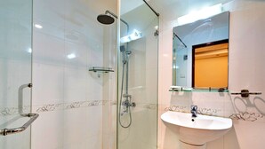 Un baño moderno con ducha de vidrio, un lavabo blanco y un espejo sobre él.