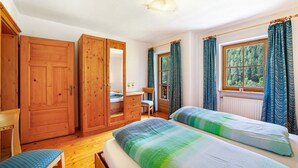 A room with two beds, a wooden wardrobe, a desk with a chair, and a window with curtains. - Apartment "Innerkaserbach" with Mountain View & Shared Garden (St. Pankraz)
