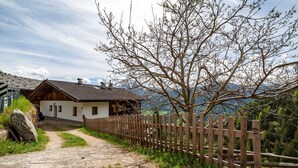 A rustic house with a dirt path leading to it, surrounded by a wooden fence and a large tree. - Apartment "Innerkaserbach" with Mountain View & Shared Garden (St. Pankraz)