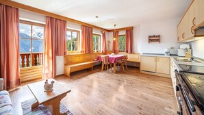 A cozy kitchen with wooden cabinets, a dining table, and a bench. - Apartment "Innerkaserbach" with Mountain View & Shared Garden (St. Pankraz)