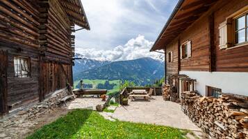 Una baita di legno con un patio in pietra, un tavolo e sedie di legno.