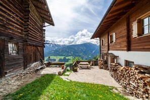 A wooden cabin with a stone patio, a wooden table, and chairs. - Apartment "Innerkaserbach" with Mountain View & Shared Garden (St. Pankraz)