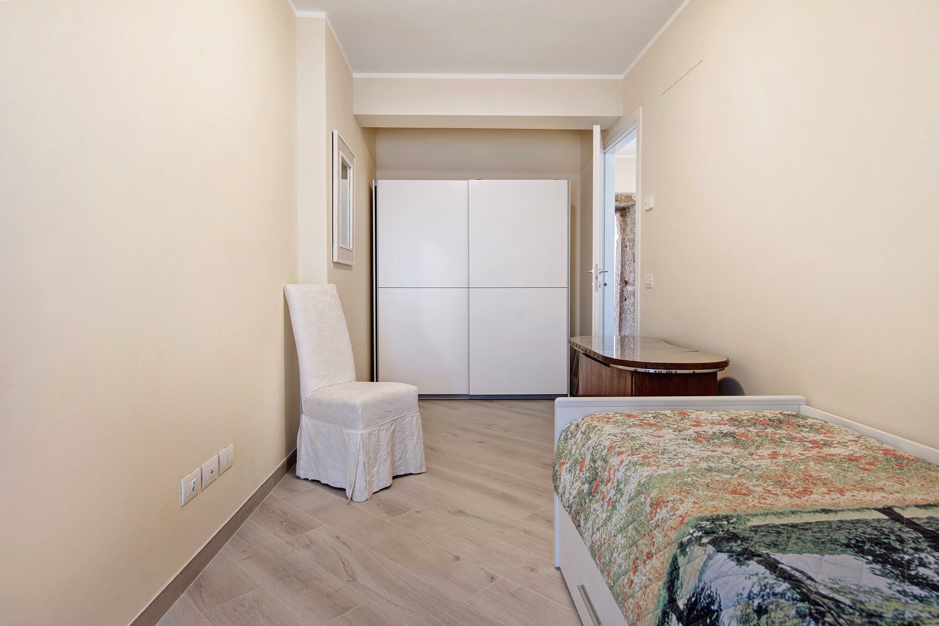 Ein Schlafzimmer mit Bett, Stuhl, Schreibtisch und Kleiderschrank.