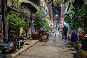 Una calle estrecha flanqueada por edificios, algunos con terrazas y plantas.