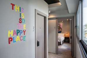 Un pasillo con un letrero colorido que dice "THIS IS SO THE HAPPY PLACE" y una puerta marcada con el número 3.