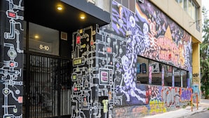 Un edificio con una reja negra, una ventana con el número 8-10, y un mural de grafiti colorido en la pared.
