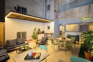 A modern interior with a sofa, chairs, a dining table, and potted plants.