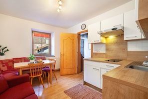 Une cuisine compacte avec un coin repas, des meubles en bois, un four encastré et une fenêtre offrant une belle vue.