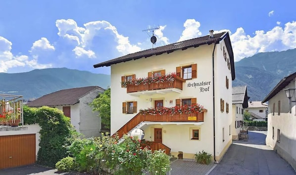 A two-story building with balconies, a staircase, and a sign reading 'Schneider Hof.'