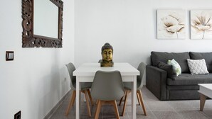 Un comedor con una mesa blanca, sillas grises y una estatua de Buda como centro.