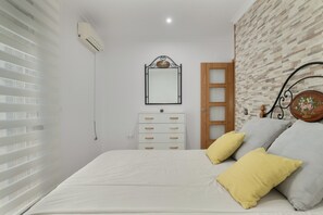 Une chambre à coucher avec un lit, une commode, un miroir et une fenêtre avec des stores.
