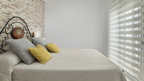 Un dormitorio con pared de ladrillos, una cama con cabecera y una ventana con persianas.