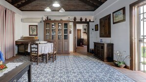 A dining area with a table, chairs, and a patterned floor. There is a kitchen area with cabinets and a window.