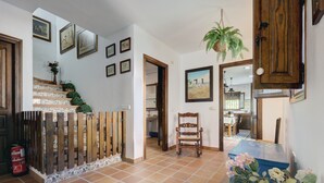 A hallway with a staircase, wooden door, and a chair.