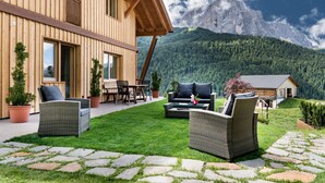 A wooden building with a patio area, outdoor furniture, and a mountain view.