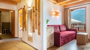 A room with wooden beams, a red plaid sofa, a small table, and a window with a view of a mountain.