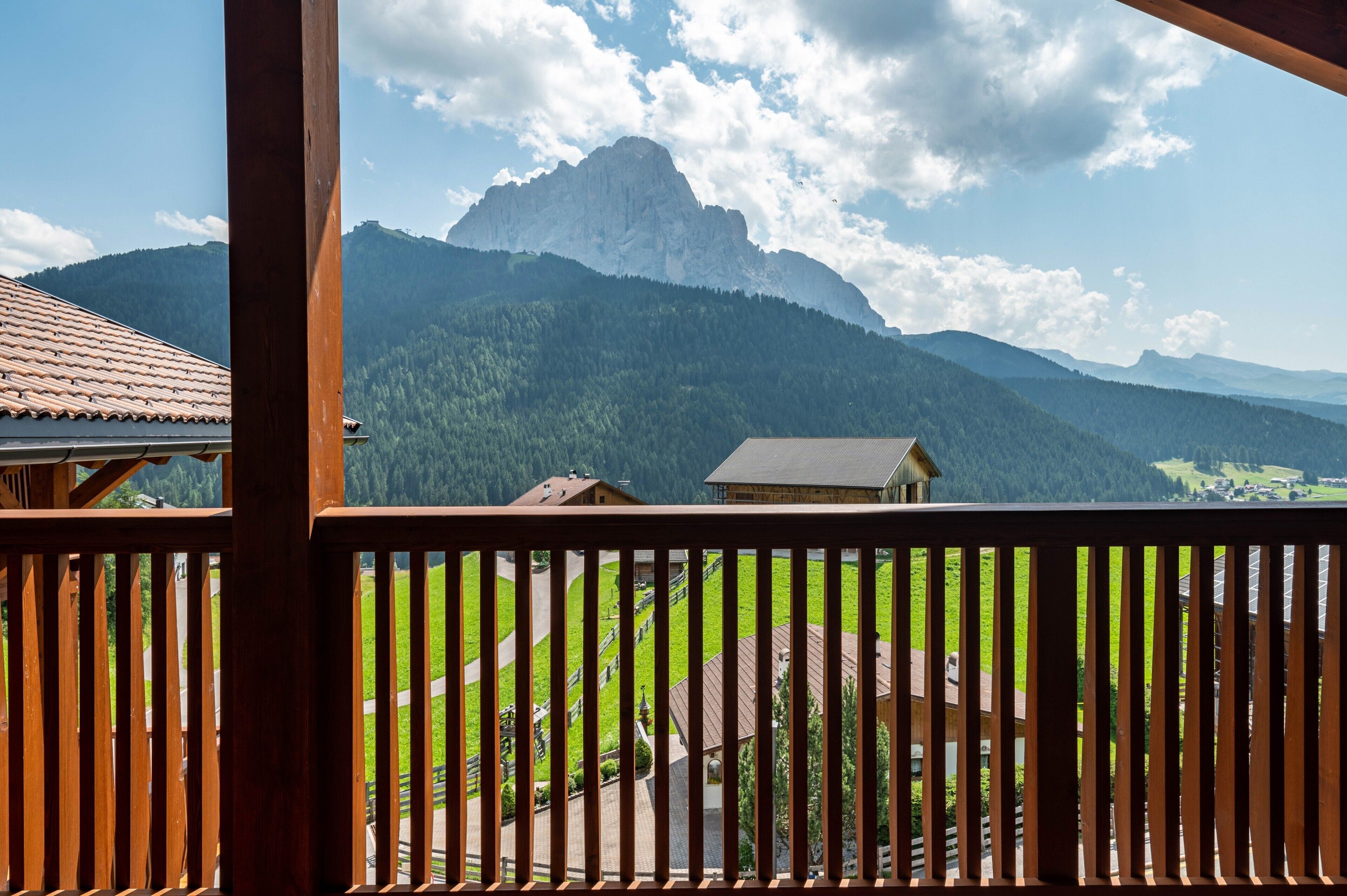 Une vue sur les montagnes depuis un balcon en bois, avec un ciel dégagé.