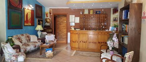 A living room with a sofa, armchairs, a coffee table, a wooden cabinet, and a bookshelf.