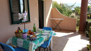 A table set outdoors with a view of the sea, a window with shutters, and a door. - Apartment 'Agriturismo Heaven Trilocale 1' with Mountain View, Shared Pool and Wi-Fi (ricadi)