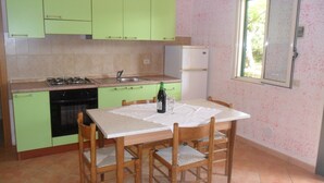 A kitchen with green cabinets, a dining table with chairs, a window, and a refrigerator. - Apartment 'Agriturismo Heaven Trilocale 4' with Sea View, Shared Pool and Wi-Fi (ricadi)