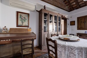 Een eetruimte met een houten tafel, stoelen, een kast met glazen deuren en een ingelijste foto aan de muur.