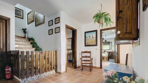 A staircase with patterned tiles, a wooden chair, and a blue chest of drawers with flowers.