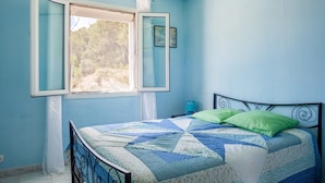 A bedroom with a bed, a window, and a view of trees.