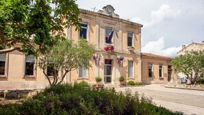 A historic building with a clock tower, flag decorations, and a well-maintained garden.