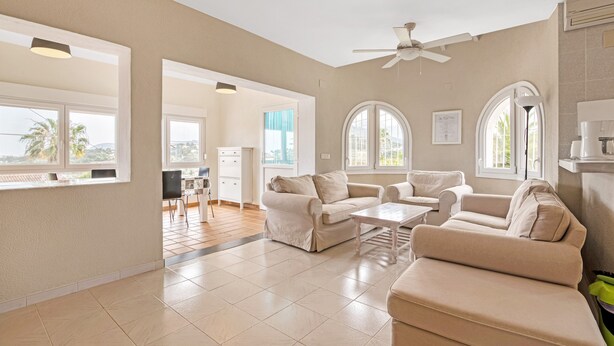 A spacious living room with a ceiling fan, large windows, and a view of the outdoors. - Villa 'Casa Leuki' with Sea/Mountain Views, Pool, Garden, Wi-Fi & AC (Calpe)