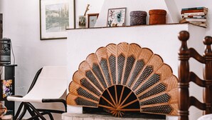 A room with a white chair, a wooden bed frame, a decorative fan, and a shelf with books and a framed picture. - Holiday Home "Villa Margherita" with 2 Private Terraces and Wi-Fi (Geremeas)