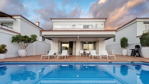 Une maison moderne dotée d’une piscine, d’une façade blanche et d’un patio couvert.