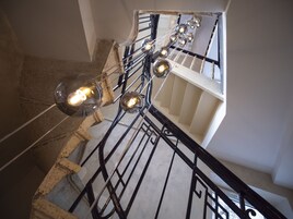 Una escalera con barandilla de metal y lámparas colgantes.