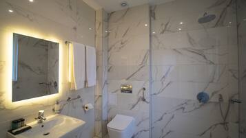 Een moderne badkamer met een marmeren douche, een wastafel en een toilet.