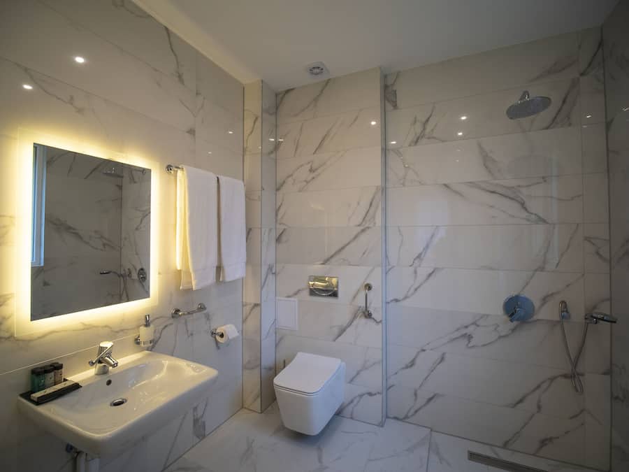 Een moderne badkamer met een marmeren douche, een wastafel en een toilet.