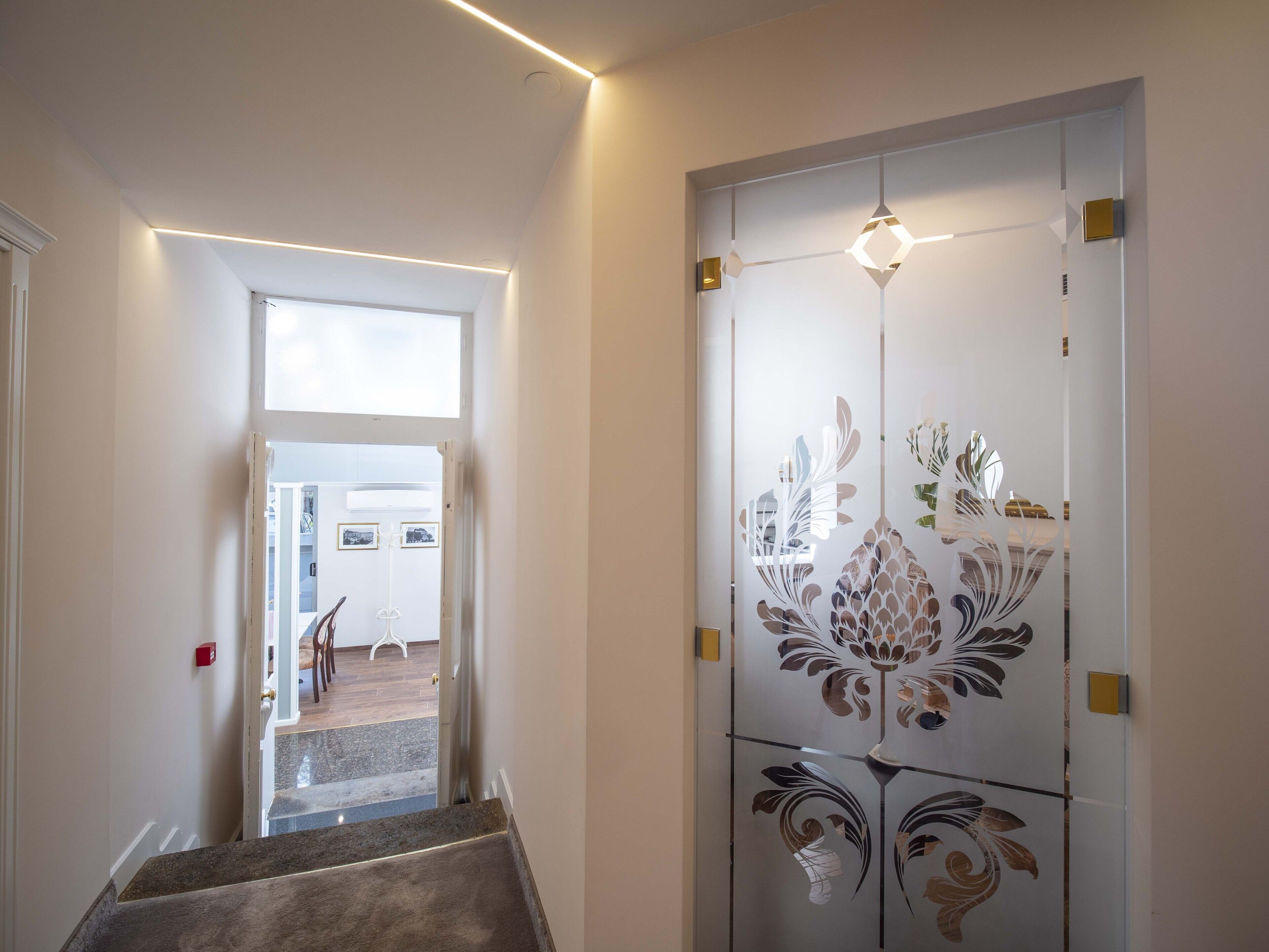 Una escalera conduce a una habitación con una puerta decorativa que presenta motivos florales.