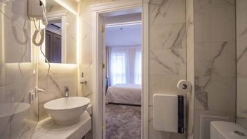 A modern bathroom with a large white sink, a hairdryer, and a toilet.