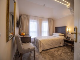 A hotel room with a bed, a chair, a desk with a lamp, and a telephone.
