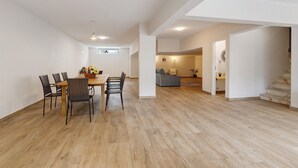 Ein großzügiger Wohnbereich mit Esstisch und Stühlen, einer Couch und einer Treppe.