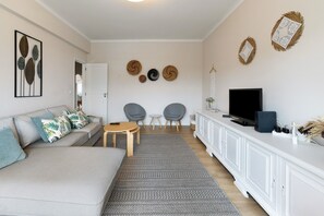 Un salon comprenant un canapé, deux fauteuils, un téléviseur et un meuble.