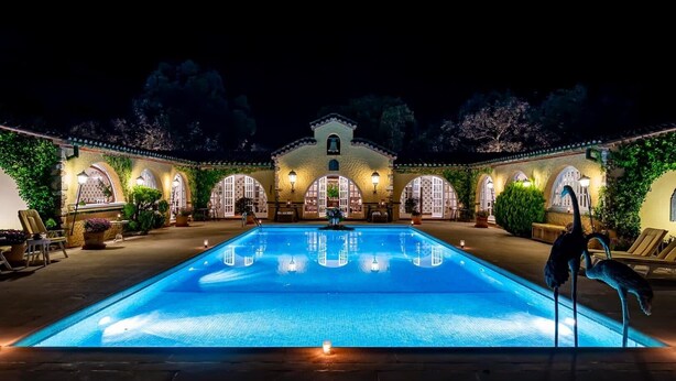 Ein Pool mit einer Springbrunnen, umgeben von Bogenfenstern und Sitzmöglichkeiten im Freien.