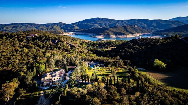 A hillside property with a pool, surrounded by dense forest and mountains.