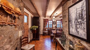 Ein Zimmer mit Steinwänden, Holzmöbeln, einem großen gerahmten Stadtbild und einer traditionellen Holztür.