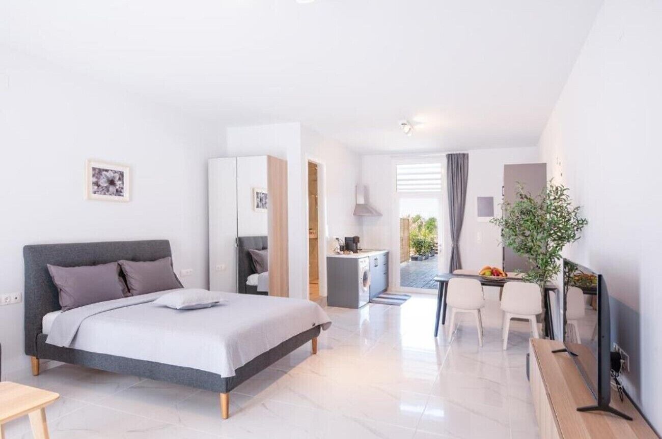 Une chambre d’hôtel moderne équipée d’un lit, d’un bureau, d’une chaise, d’une télévision et d’un petit coin cuisine.