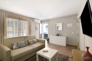 A modern living room with a sofa, a coffee table, a white cabinet, and a TV.