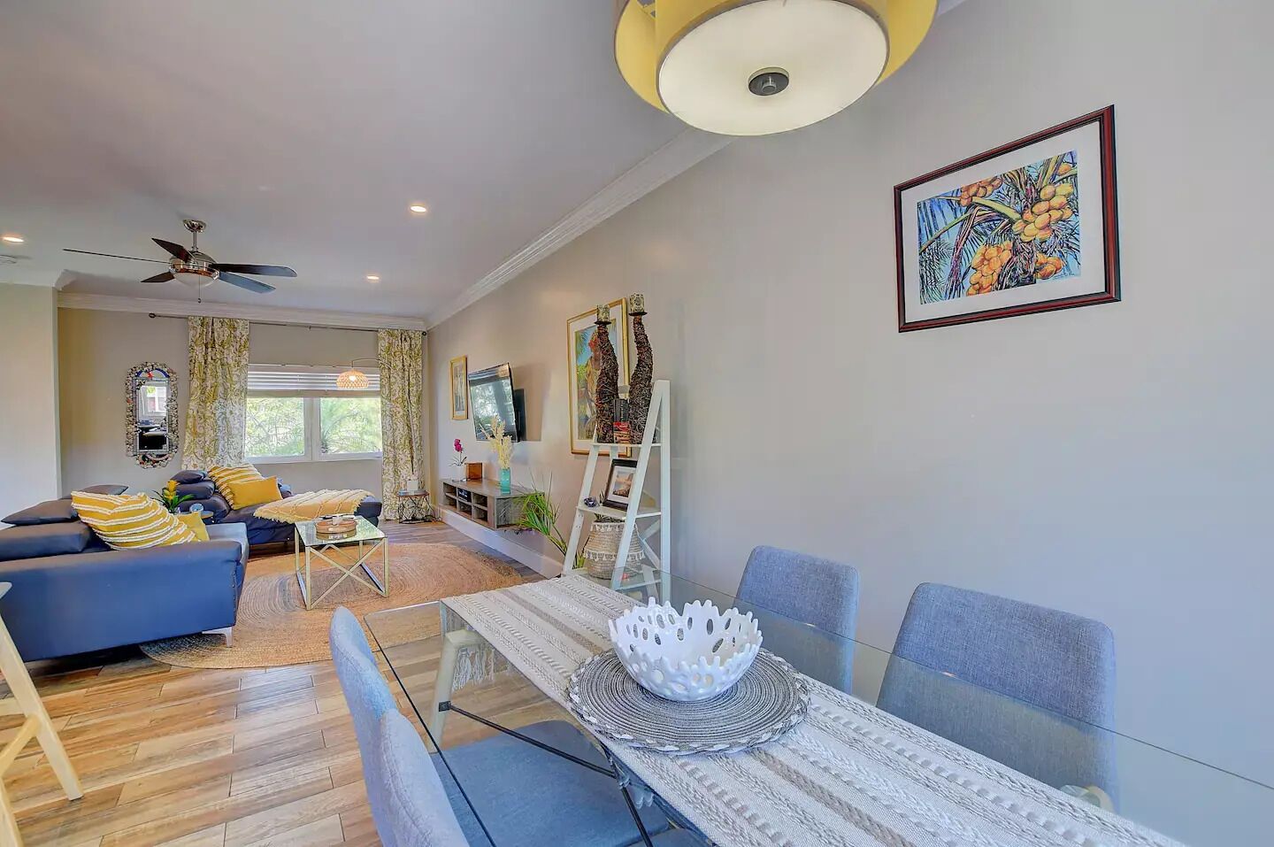 A modern living room with a sofa, coffee table, and a dining area with a glass table and chairs.
